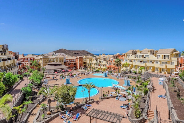 A resort with multiple swimming pools, sun loungers, and a central gazebo.