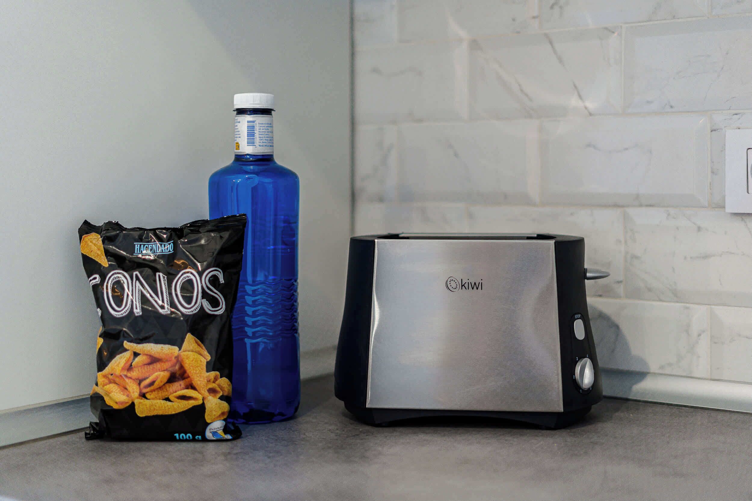 A kitchen counter with a bag of ONOS chips, a blue water bottle, and a toaster.