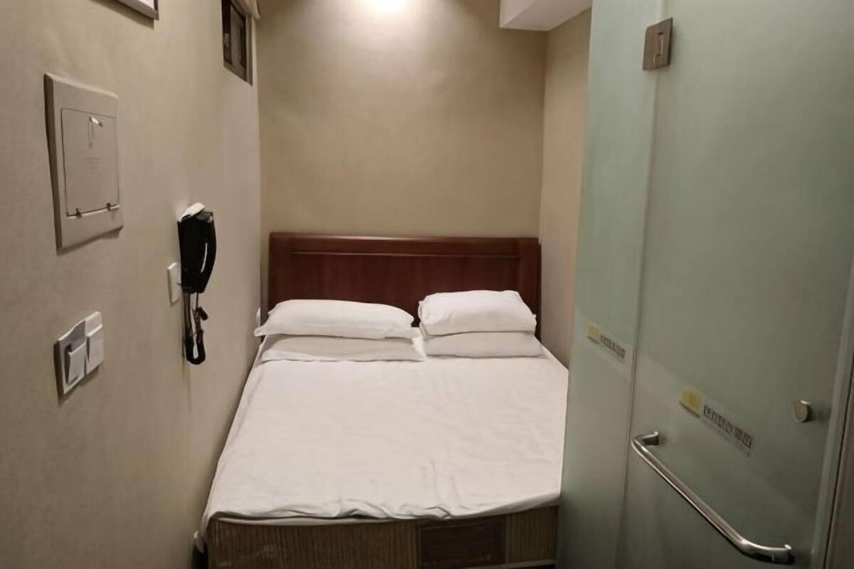 Ein Hotelzimmer mit einem Bett, einem Telefon und einer Tür mit Griff.