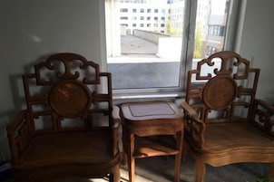 Dos sillas de madera y una mesita en una habitación con ventana.