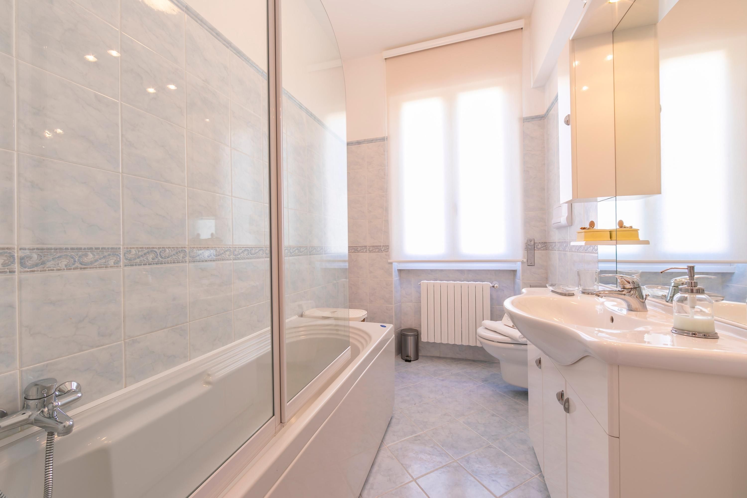 Un baño moderno con ducha envuelta en vidrio, una bañera independiente, un lavabo con espejo y un inodoro.