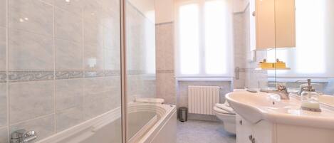 Un baño moderno con ducha envuelta en vidrio, una bañera independiente, un lavabo con espejo y un inodoro.