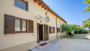 A building with a beige facade, wooden shutters, a glass door, and a gravel driveway.