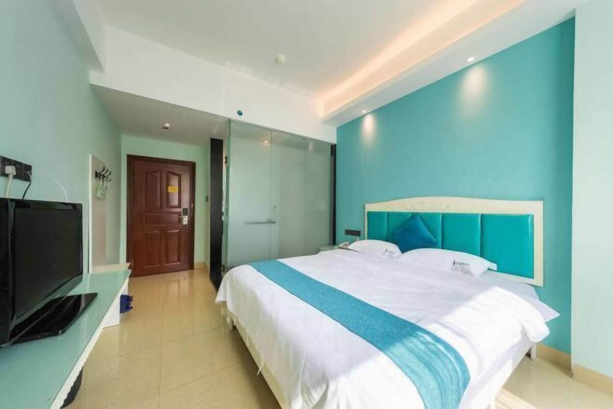 A hotel room with a bed, a television, and a door.