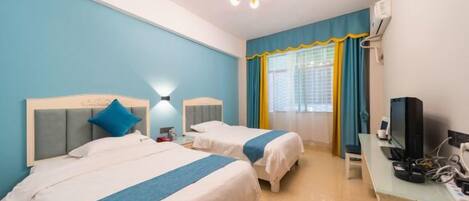 Una habitación de hotel con dos camas, un escritorio con computadora y una ventana con cortinas.
