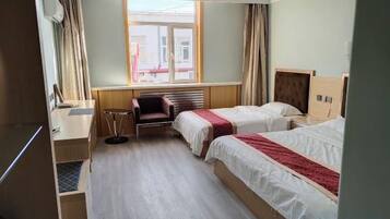 A hotel room with two beds, a desk, a chair, and a window with curtains.