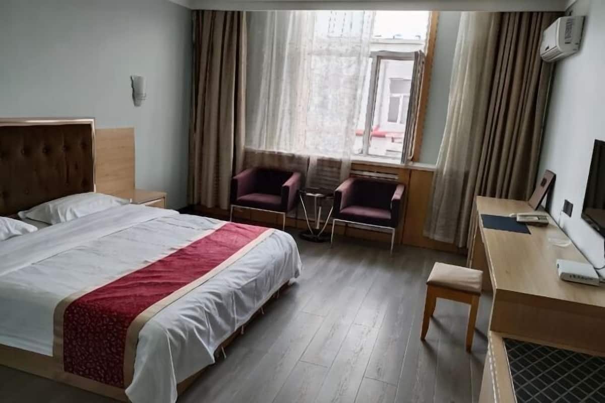Hotellihuone, jossa on sänky, työpöytä, tuoli ja pieni pöytä.