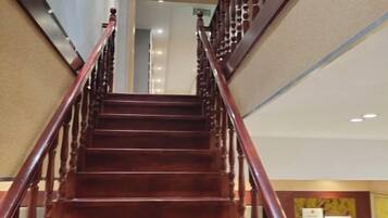 A wooden staircase with a handrail leading to an upper floor.