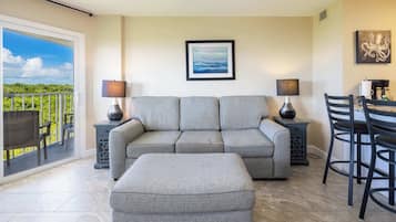 A living room with a grey sofa, two side tables with lamps, a coffee table, and a dining area with a table and chairs.