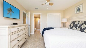 A bedroom with a bed, a dresser, a ceiling fan, a door leading to a bathroom, and a framed picture on the wall. - Ocean View Gem Ocean Pointe 3406 2BA/2BR King/Queen (Tavernier)