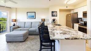 A modern kitchen with a large island, a built-in oven, and a refrigerator.