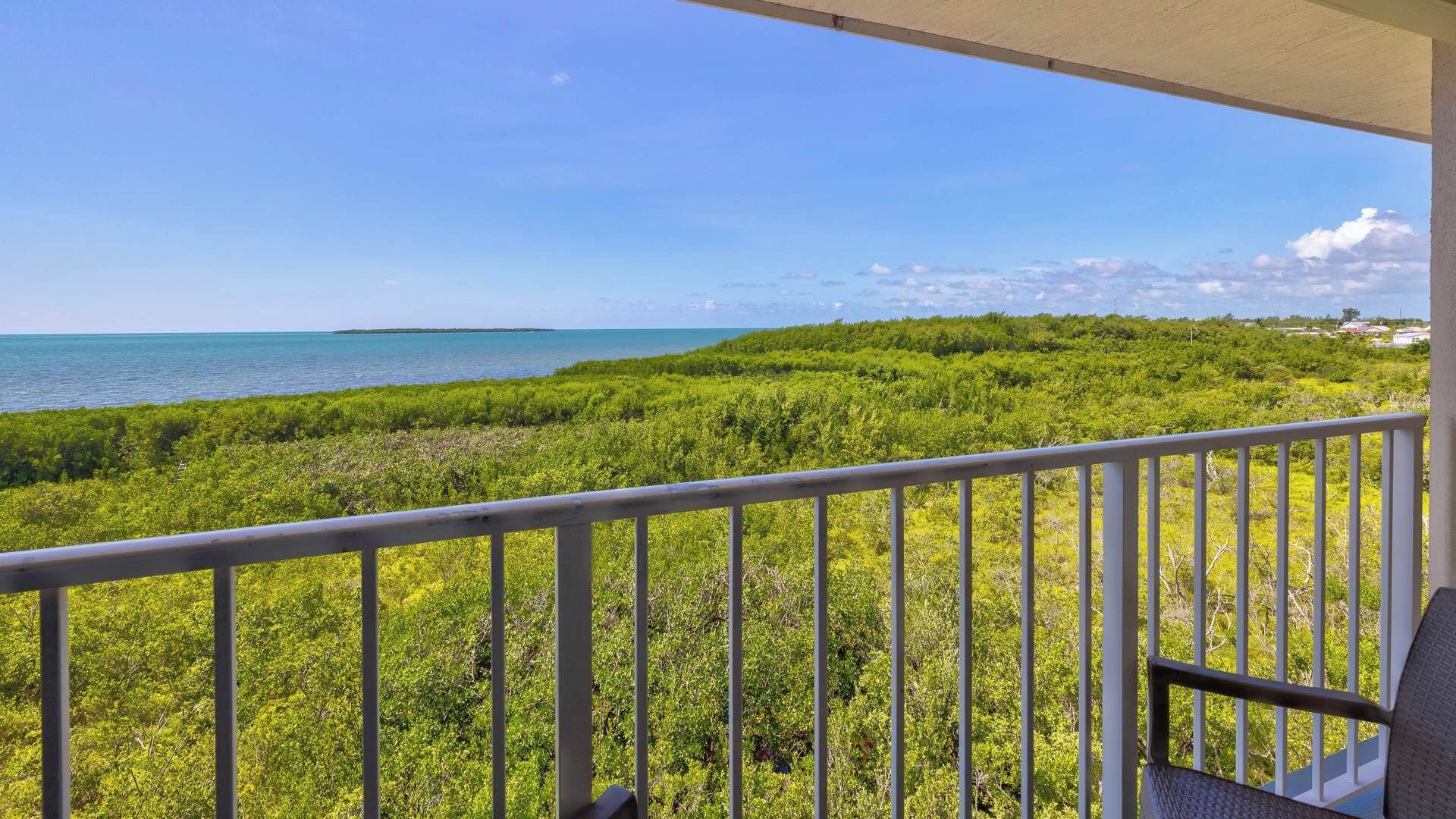 A balcony with a view of a lush green landscape and a calm sea.