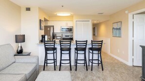 A compact living space with a kitchenette, a dining area with four chairs, a sofa, and a lamp. - Ocean View Gem Ocean Pointe 3406 2BA/2BR King/Queen (Tavernier)