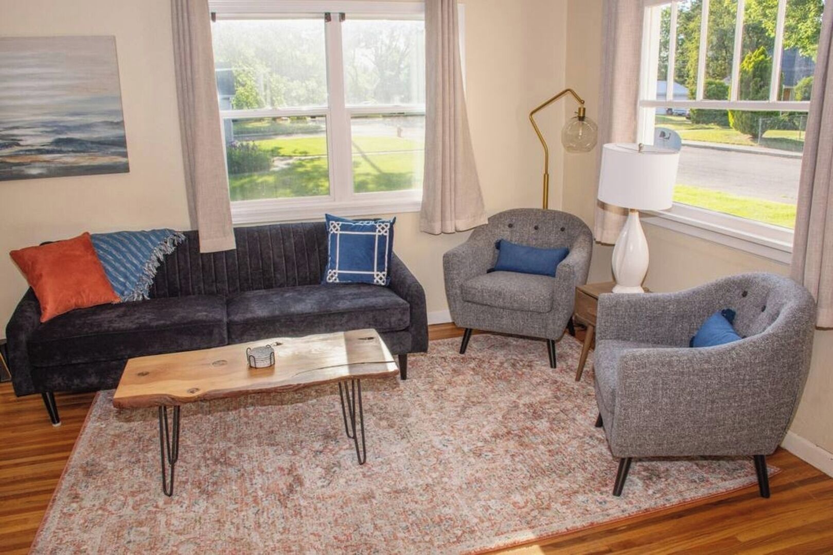 A living room with a dark sofa, two armchairs, a coffee table, and a lamp.