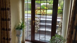 Ein Zimmer mit einer großen Glasdoor, die zu einem Außenbereich mit einem Kiesweg und einer hölzernen Bank führt.