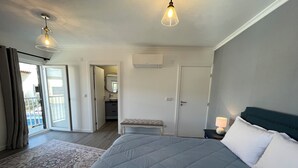 A bedroom with a large bed, a bench, a nightstand, a lamp, and a view of the outside. - Casa da Calabra by Trip2Portugal (Vila Nova de Foz Coa)