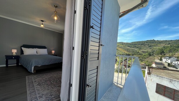 A bedroom with a bed, bedside tables, and a view of a green landscape. - Casa da Calabra by Trip2Portugal (Vila Nova de Foz Coa)