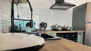 A modern kitchen with a wooden countertop, a coffee maker, a kettle, and a stove. - Casa da Calabra by Trip2Portugal (Vila Nova de Foz Coa)