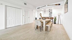 Un comedor amplio con una mesa y sillas de madera, un banco, una planta en maceta y una lámpara.
