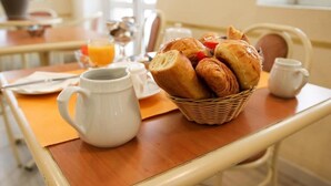 A breakfast table with croissants, a coffee pot, and a glass of orange juice. - Hotel Appia (Cannes)