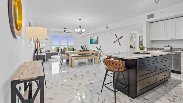 A modern kitchen with a marble countertop, wooden dining table, and bar stools.