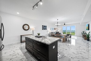 Una cucina moderna con isola in marmo, mobili neri e zona pranzo con una panca e sedie.