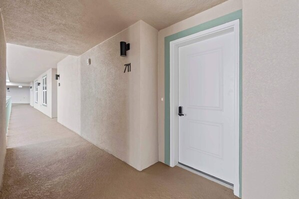 Un pasillo con puertas blancas, numeradas 711 y 712, que conduce a habitaciones individuales.
