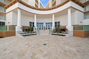 A building with a central entrance, large columns, and a tiled courtyard.