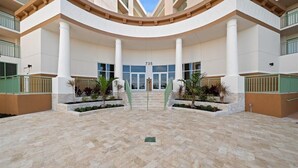 A spacious, modern hotel entrance with a curved facade, large columns, and a central staircase leading to the entrance. - RIVER FLY IN: The Cocoa, River & Runway View (Merritt Island)