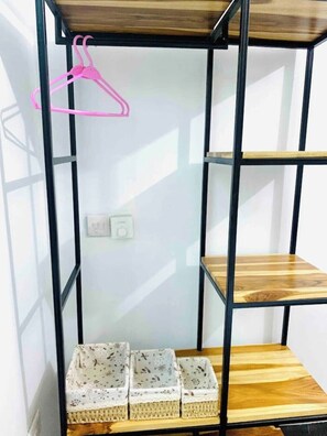 Minimalist room with a black shelving unit, wicker baskets, and a wooden top shelf.