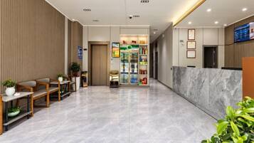 A hotel lobby with a reception desk, seating area, and a refreshment kiosk.