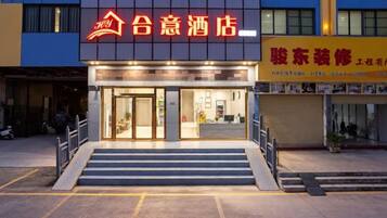 A hotel entrance with a staircase leading up to the door, a sign above the entrance, and a closed shop to the right.
