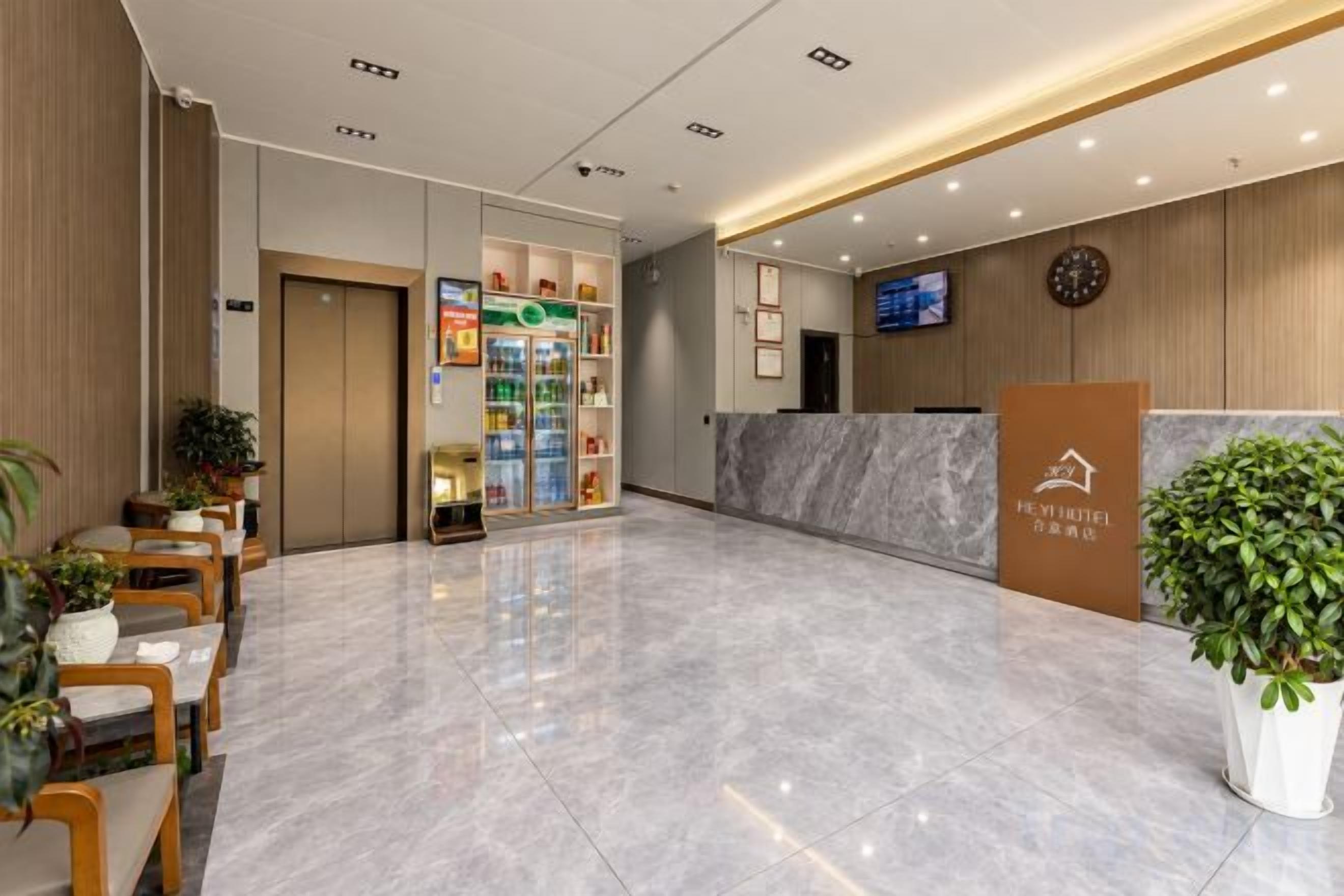A hotel reception area with a marble floor, a reception desk, a clock, and a television screen.