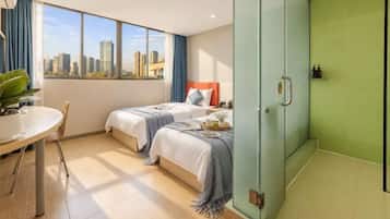 A hotel room with two beds, a dining table, and a city view.