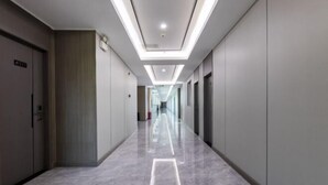 A modern hotel corridor with a long, straight layout, a clean, tiled floor, and a ceiling with recessed lighting. - Heyi Express Hotel (Zhuhai Baijiao Science Park Doumen Bus Terminal) (Zhuhai)
