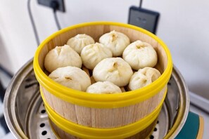 A bamboo steamer with several white steamed buns. - Heyi Express Hotel (Zhuhai Baijiao Science Park Doumen Bus Terminal) (Zhuhai)