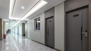 A modern hallway with a shiny floor, a door with a number sign, and a window. - Heyi Express Hotel (Zhuhai Baijiao Science Park Doumen Bus Terminal) (Zhuhai)
