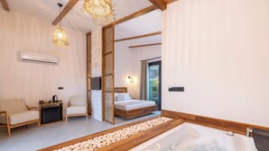 Quarto moderno com banheira de madeira, cama e área de estar.