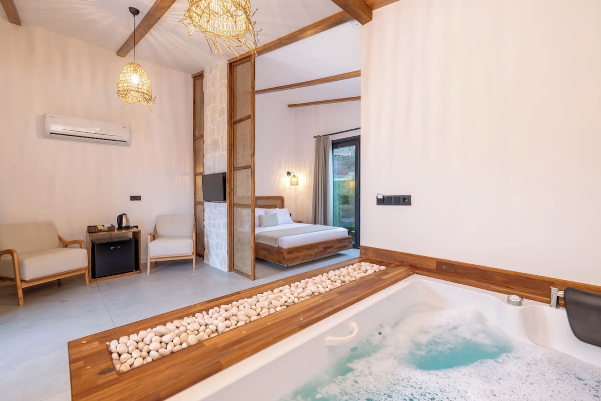 A modern bedroom with a wooden bathtub, a bed, and a seating area.