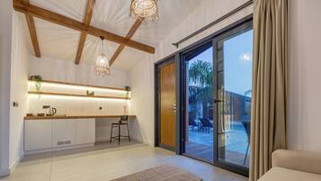 Una cocina moderna con isla integrada, iluminación colgante y un puerta corrediza de vidrio que da a un patio exterior.