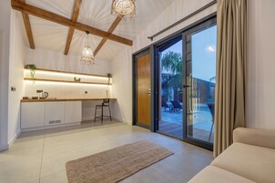 Una cocina moderna con isla integrada, iluminación colgante y un puerta corrediza de vidrio que da a un patio exterior.
