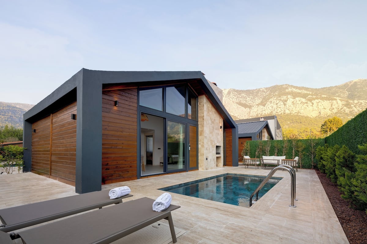 A modern house with a swimming pool, wooden exterior, and large windows.