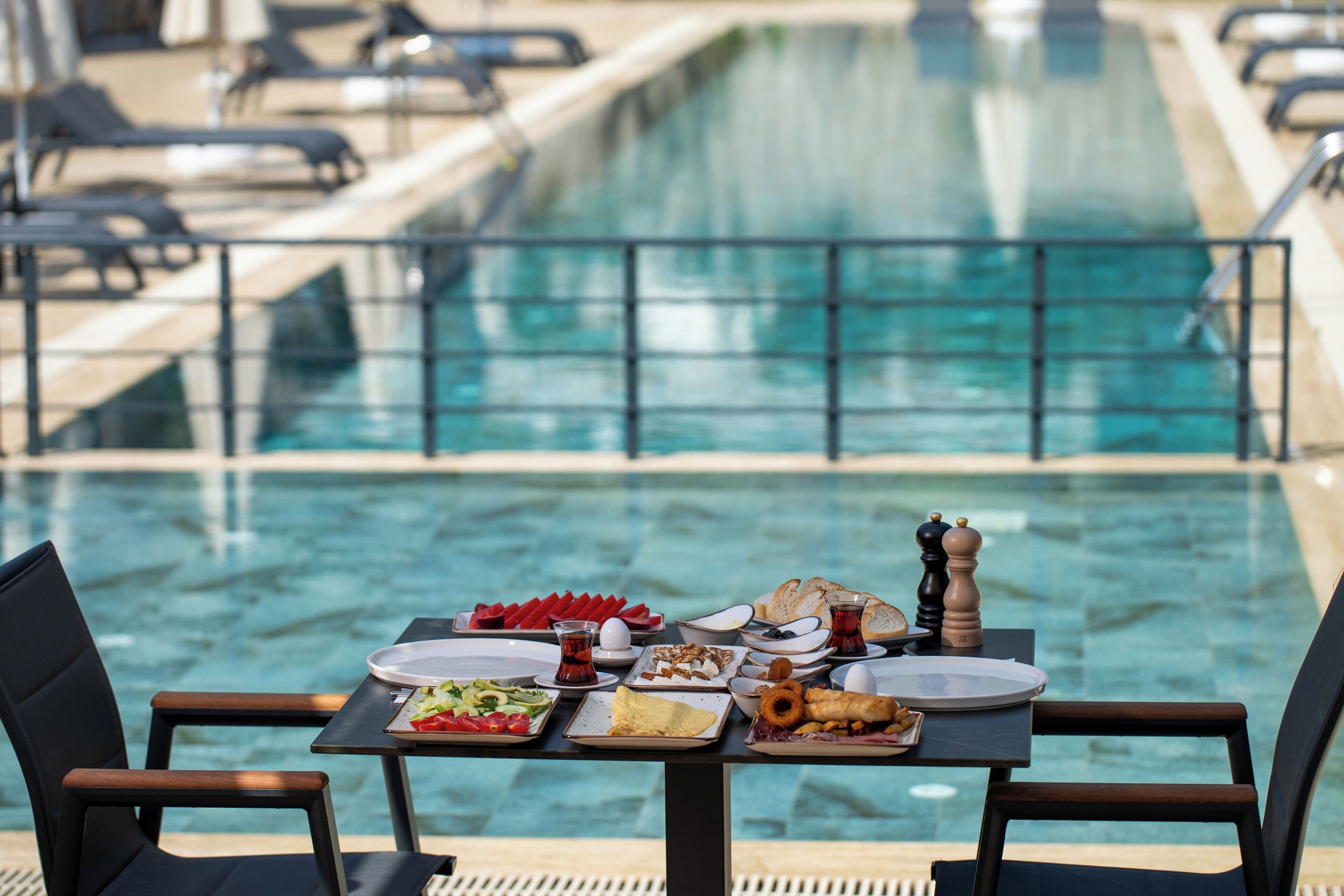 Une table à manger dressée avec une variété de plats, donnant sur une piscine.