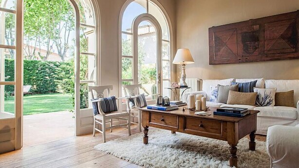 Une pièce spacieuse avec une grande fenêtre, un canapé blanc, une table basse en bois et un fauteuil.
