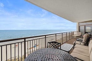 Ein Balkon mit Blick auf das Meer, einem Tisch und Stühlen.