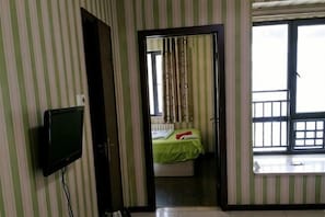 Una habitación con cama, televisión, ventana con vistas y puerta que da a otra estancia.