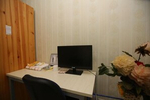 A room with a wooden panel wall, a desk with a computer, a chair, and a vase of flowers. - Zhengzhou Ruxinjia Apartment (Zhenghong Digital Apartment) (Zhengzhou)