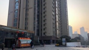 Un edificio residencial alto con un patio que incluye un carrito de comida y un diseño circular de piedra.