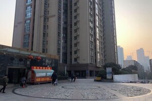 Ein Hochhaus mit Wohnetagen und einem Innenhof, der einen Imbisswagen und ein kreisförmiges Steinmuster zeigt.