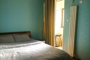 A bedroom with a bed, curtains, and a radiator. - Zhengzhou Ruxinjia Apartment (Zhenghong Digital Apartment) (Zhengzhou)